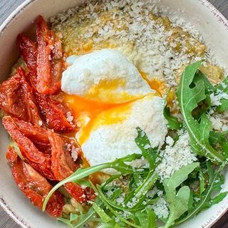 Плющена вівсянка з песто, вʼяленими томатами і яйцем пашот