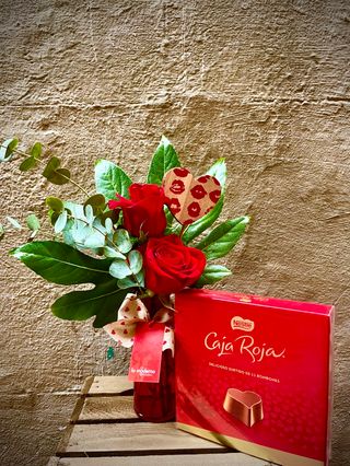 Jarrón con dos rosas rojas y caja de bombones.
