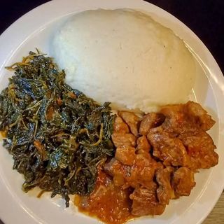 White ugali served with beef in Nigerian spicy sauce with managu-terere