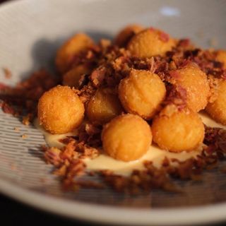 Картопляні крокети з сирним соусом, цибулевими чіпсами та крихтами бекону