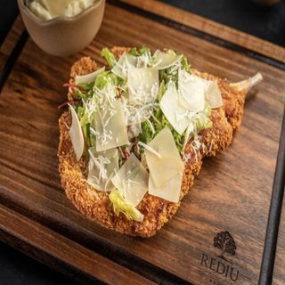 Șnițel de porc cu os și piure de cartofi, salată verde, parmezan