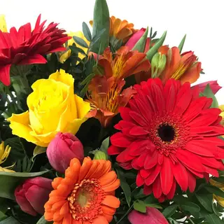 Rosa rossa centrale in bouquet di fiori misti di stagione (prevalenza rosso/giallo/arancio)
