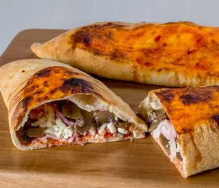 Calzone con mozzarella, salame, scamorza, pomodoro sopra e peperoncino