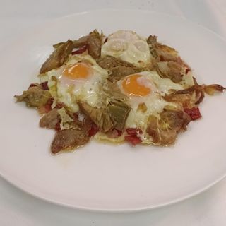 Huevos rotos con alcachofas y jamón
