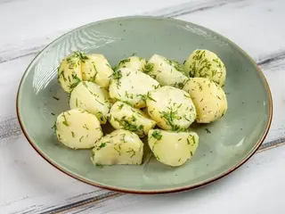 Відварена молода картопля з вершковим маслом, часником та зеленню (250g)