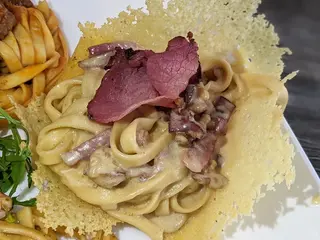 Fettuccine con speck, taleggio e noci in cialda di parmigiano