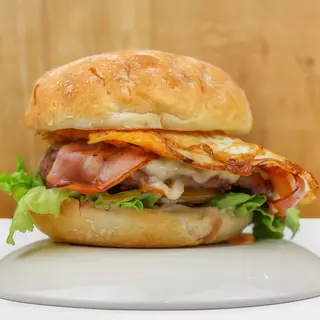 BURGER ÑAM: Carne 100% vacuno (180grs) con queso fundido, beicon crujiente, huevo frito, mayonesa y vegetales (Mezcla de lechugas y tomate)