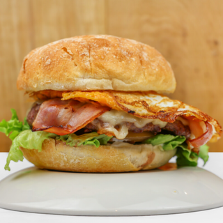 BURGER ÑAM: Carne 100% vacuno (180grs) con queso fundido, beicon crujiente, huevo frito, mayonesa y vegetales (Mezcla de lechugas y tomate)