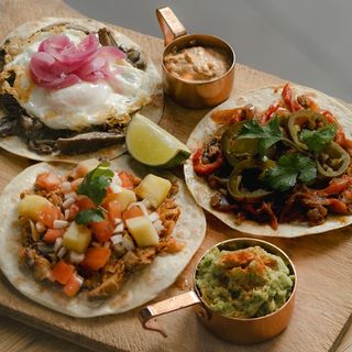 surtido de tacos acompañados de guacamole, salsa sour, lima