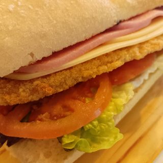 Milanesa de pollo, con tomate, lechuga, jamón York y queso.