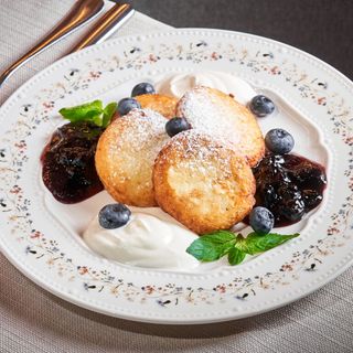 Papanași dulci din brânză fină, cu smântână și fructe de sezon