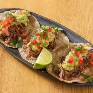 Tacos de pato confitado servidos con cebolla caramelizada (3 uds.)