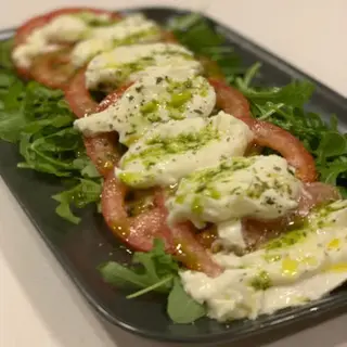 Rucula, tomate fresco en rodajas, mozzarella di bufala y pesto servido con focaccia