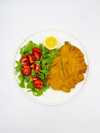 Cotoletta di vitello l'orecchia d'elefante con rucola, pomodorini e limone