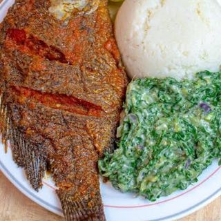 White ugali served with fish in Nigerian stew and creamed spinach 
