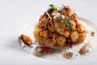 Cavolfiore fondente speziato su fondo di verdure e nocciole, servito con gambi di porcino