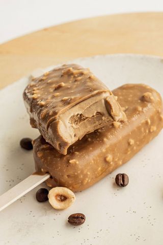 Inghețată vegana cu cafea învelită în ciocolată alba cu alune de pădure-85g