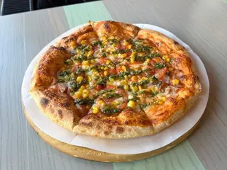 Піца з шинкою, кукудзою, томатами та соусом песто