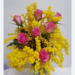 Cinque rose rosa ben confezionate con mimosa