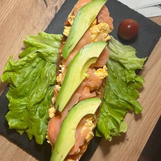 Tostada con huevos revueltos, salmón, aguacate y tomate