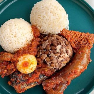White rice and oloyin beans served with boiled egg, pomo shaki, and titus fish