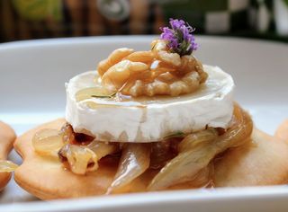 Tapa de tostada de cebolla caramelizada, queso de cabra, nueces y salsa oporto
