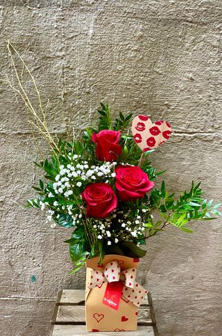 Jarrón resistente al agua con tres rosas rojas.