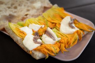 Pizza artigianale con fiori di zucca, alici e mozzarella.