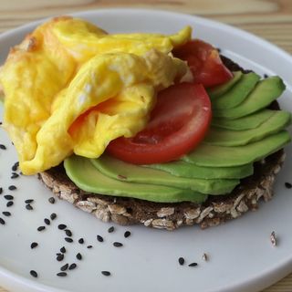 Tostada tortilla, aguacate laminado y tomate