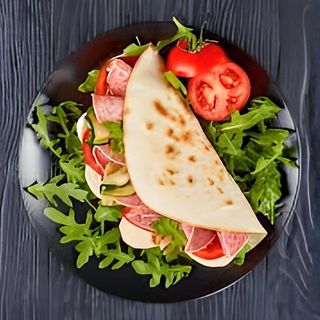 Piadina con salame piccante, fontina, insalata, pomodoro e salsa
