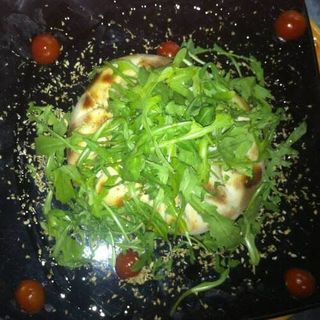 Queso provolone fundido con tomate cherry y rúcula