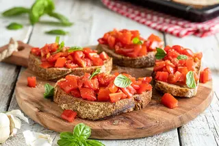 Tagliere di bruschette al pomodoro e profumo di basilico