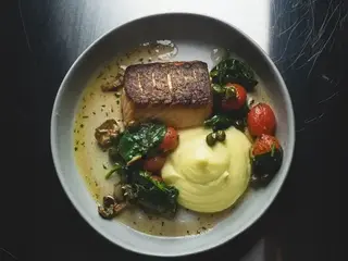 Grilled salmon with mashed potatoes, tomatoes, olives and capers