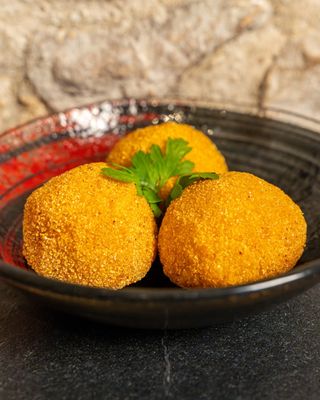 Arancini con sfufato di maiale su crema di piselli e fonduta di Ragusano