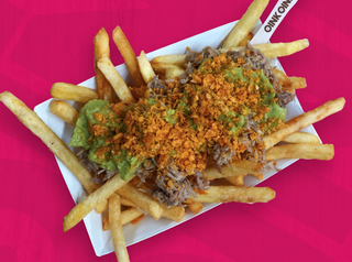 Patatas con cerdo asado, guacamole, trozos de nachos y salsa queso cheddar