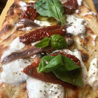 Pinsa con burrata, olive, capperi, pomodori secchi e acciughe