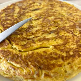 Tortilla de patatas y cebolla con pan con tomate.