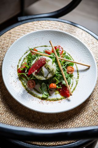 Ensalada de Burrata sobre rúcula, cherrys y mermelada de pimientos.