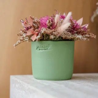 Vaso cerâmico pequeno verde com as flores preservadas rosa