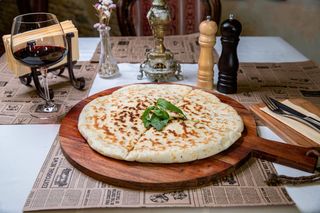 Placinta coapta pe vatra cu branza de oaie si verdeturi 