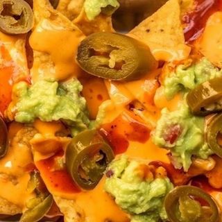 Nachos con formaggio, guacamole, jalapeno e salsa