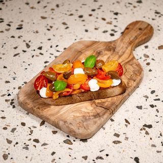 Pane bruscato con datterini gialli e rossi, ciuffi di ricotta e olive