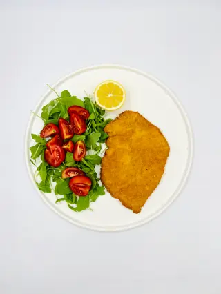 Cotoletta di pollo con rucola, pomodorini e limone