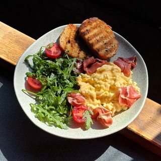 Скрембл з хамоном, сирним соусом, руколою, томатами чері і тостами