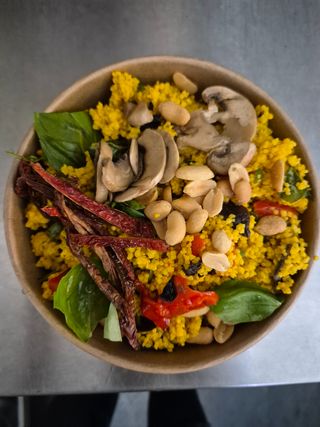 Riso nero con caponata di verdure, scarole, olive nere, uva passa, pomodori secchi e noci