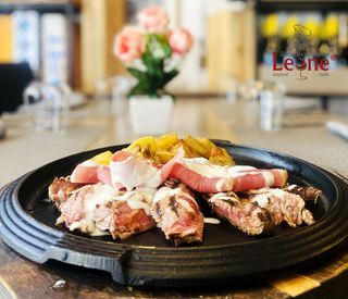 Tagliata di vitello su pietra lavica con fonduta di parmigiano e crudo