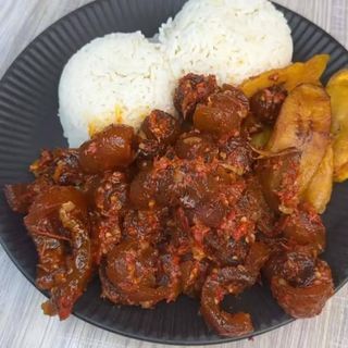 White rice served with peppered pomo and plantains 