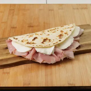 Piadina con cotto arrosto, brie, patate, crema di Grana Padano, rucola