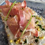 Bruschetta Con jamon serano, queso crema y pistachos picados