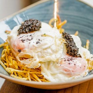 Huevos rotos con crema de trufa y escamas de patata